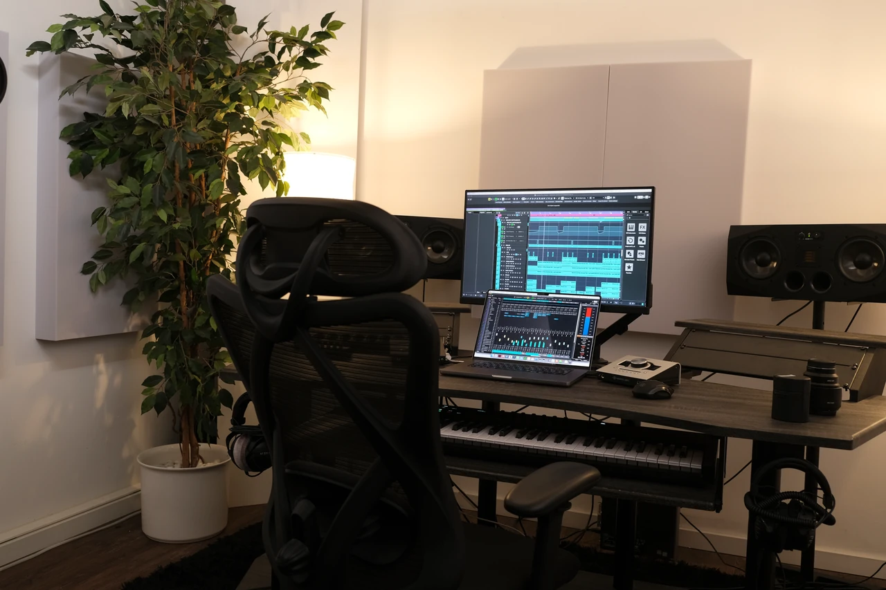 Arbeitsplatz mit Studiostuhl, Bildschirm, Laptop und Keyboard