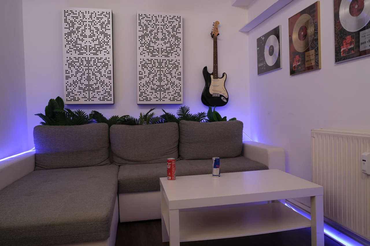 Lounge-Bereich mit Sofa, E-Gitarre und Auszeichnungen an der Wand